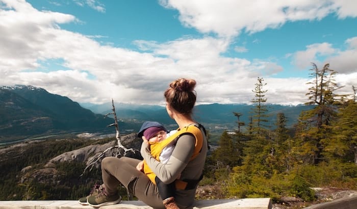 woman sitting at the top of a mountain with a baby in a baby carrier