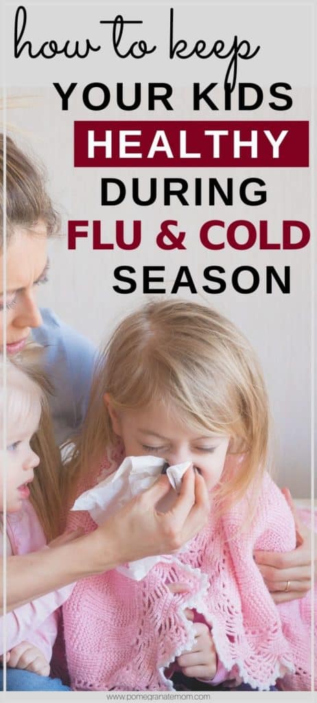 Pinnable image of a mom cleaning her sneezing girl's nose with text reading How to keep your kids healthy during flu & cold season