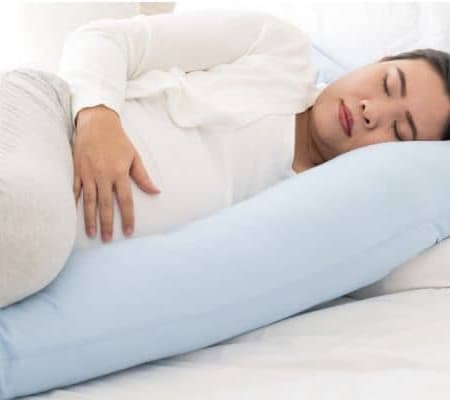 Pregnant woman lying with a body pillow as a pregnancy must have