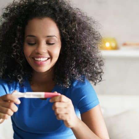 Happy woman smiling for joy with pregnancy test.