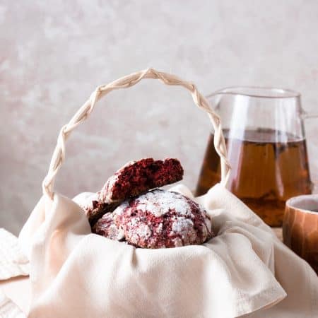 Red velvet Valentine cookies in a basket with a glass pincher of tea