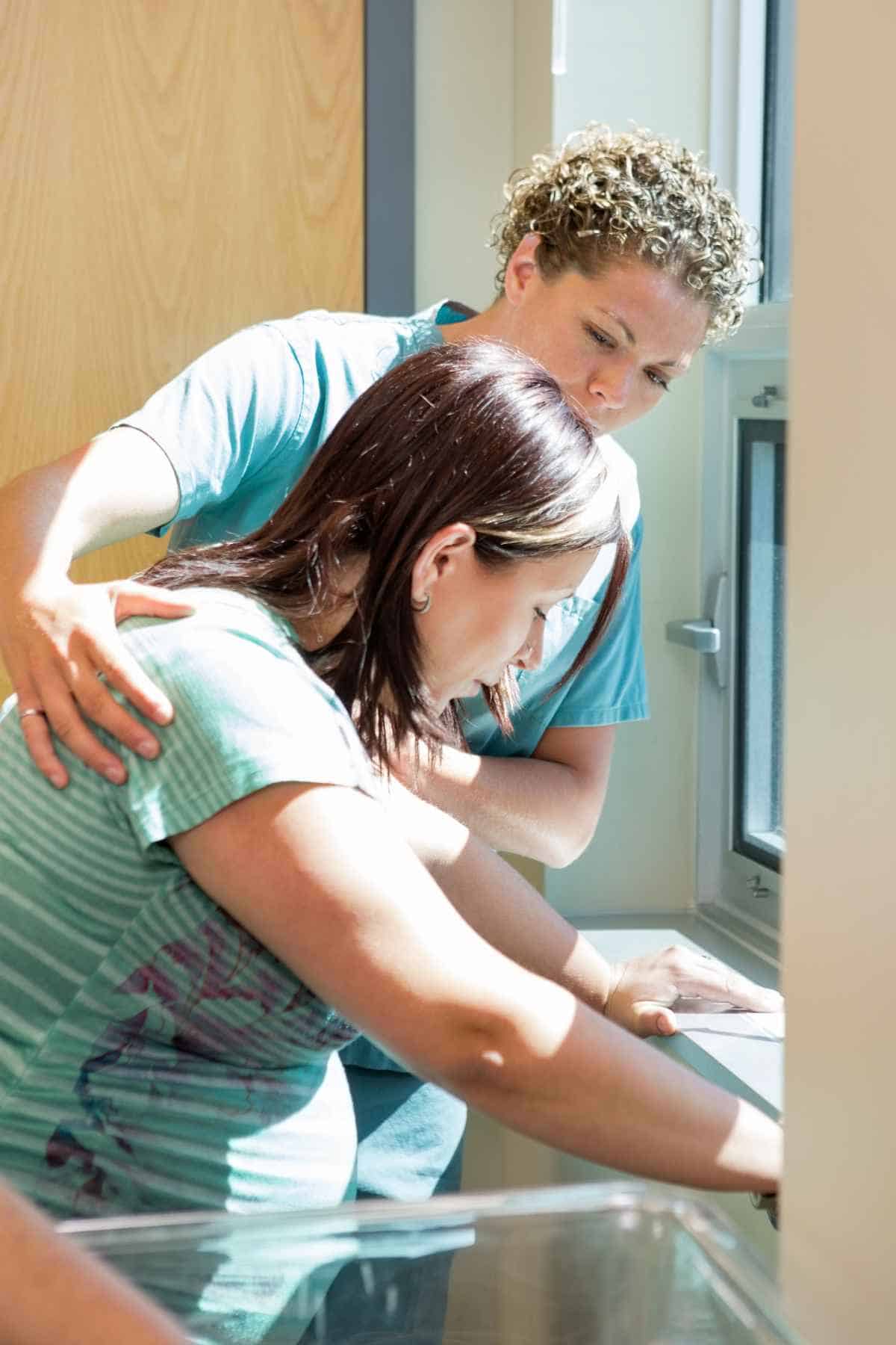 labor and delivery nurse helping pregnant woman