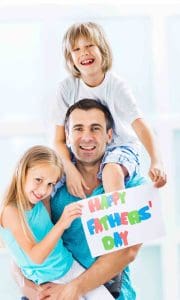 father with his two kids with handmade card that reads happy Father's Day